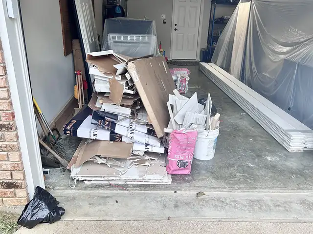 Garage with stacked drywall scraps and renovation debris before removal